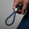 Hand holds keychain sailing rope navy blue white blue, stainless steel frame with engraving visible