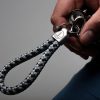 Hand holds keychain sailing rope silver gray navy blue, stainless steel frame with engraving visible