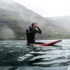 Surfer auf Surfbrett im Salzwasser trägt Fischers Fritze-Armband aus Segeltau