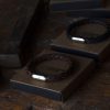 Two bracelets braided leather brown and gift boxes lie on workbench in the Fischers Fritze-workshop